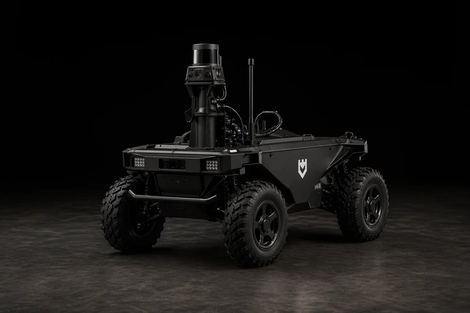 Grayhaven unmanned ground vehicle, three-quarter front view, showing LiDAR dome, multi-spectral camera mast, telemetry antenna, LED headlight clusters, and shield insignia on the side panel